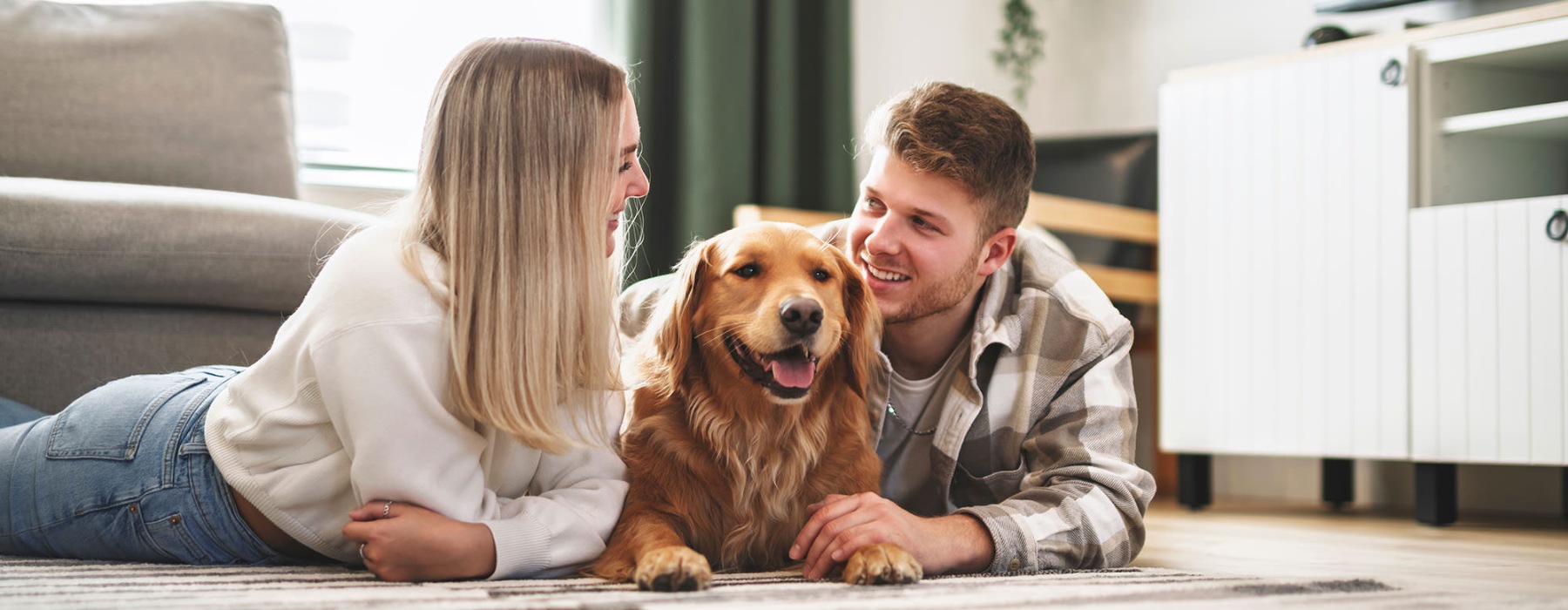 a couple lays on the floor with their dog
